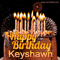 A rich chocolate cake topped with glowing birthday candles and surrounded by bright fireworks. The animated GIF displays the message 'Happy Birthday Keyshawn' in golden text.