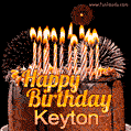 A rich chocolate cake topped with glowing birthday candles and surrounded by bright fireworks. The animated GIF displays the message 'Happy Birthday Keyton' in golden text.