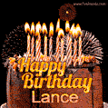 A rich chocolate cake topped with glowing birthday candles and surrounded by bright fireworks. The animated GIF displays the message 'Happy Birthday Lance' in golden text.