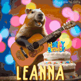 Animated birthday GIF showing a capybara playing guitar and singing beside a birthday cake with the name Leanna in large letters and colorful bokeh lights in the background.