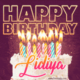 A colorful birthday cake topped with lit candles, with the words 'Happy Birthday Lidiya' in bold glowing letters on a burgundy background. Animated flames add a festive touch.