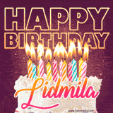 A colorful birthday cake topped with lit candles, with the words 'Happy Birthday Lidmila' in bold glowing letters on a burgundy background. Animated flames add a festive touch.