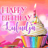 A vibrant birthday GIF featuring a rainbow-colored cupcake topped with white frosting, sprinkles, and a lit candle. The text reads 'Happy Birthday Luludja' in bold pink and violet letters with white outline.
