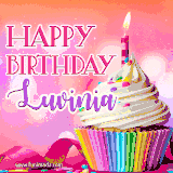 A vibrant birthday GIF featuring a rainbow-colored cupcake topped with white frosting, sprinkles, and a lit candle. The text reads 'Happy Birthday Luvinia' in bold pink and violet letters with white outline.
