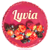 Beautifully decorated red velvet berry birthday cake with vibrant fruits and a glowing 'Lyvia' name, adding a touch of sweetness and sparkle.