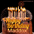 A rich chocolate cake topped with glowing birthday candles and surrounded by bright fireworks. The animated GIF displays the message 'Happy Birthday Maddox' in golden text.