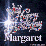 Close-up of a silver crown with emeralds, rubies, and sapphires resting on crystal-encrusted Happy Birthday text.Margaret