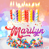 A cheerful white birthday cake with multicolor sprinkles, lit candles, and 'Marilyn' written in vibrant letters, in an animated GIF.