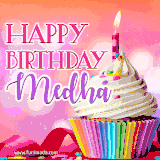 A vibrant birthday GIF featuring a rainbow-colored cupcake topped with white frosting, sprinkles, and a lit candle. The text reads 'Happy Birthday Medha' in bold pink and violet letters with white outline.