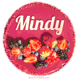 Beautifully decorated red velvet berry birthday cake with vibrant fruits and a glowing 'Mindy' name, adding a touch of sweetness and sparkle.
