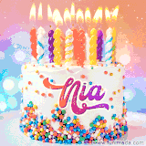A cheerful white birthday cake with multicolor sprinkles, lit candles, and 'Nia' written in vibrant letters, in an animated GIF.
