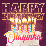 A colorful birthday cake topped with lit candles, with the words 'Happy Birthday Olayinka' in bold glowing letters on a burgundy background. Animated flames add a festive touch.