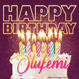 A colorful birthday cake topped with lit candles, with the words 'Happy Birthday Olufemi' in bold glowing letters on a burgundy background. Animated flames add a festive touch.
