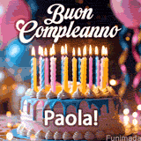 Birthday cake topped with pink and yellow lit candles, surrounded by glowing bokeh lights and party balloons. The greeting 'Buon Compleanno Paola GIF!' is displayed.