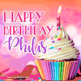A vibrant birthday GIF featuring a rainbow-colored cupcake topped with white frosting, sprinkles, and a lit candle. The text reads 'Happy Birthday Philis' in bold pink and violet letters with white outline.