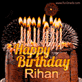 A rich chocolate cake topped with glowing birthday candles and surrounded by bright fireworks. The animated GIF displays the message 'Happy Birthday Rihan' in golden text.