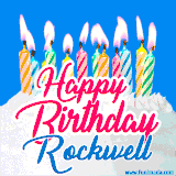 A cheerful animated GIF featuring colorful lit birthday candles on a white cake, with the text 'Happy Birthday Rockwell' in bold red and blue script on a bright blue background.