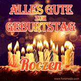 An animated GIF featuring 'Alles Gute Zum Geburtstag Roczen' in glowing red and gold letters above a cake with colorful lit candles, set against a festive sparkling background.