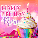 A vibrant birthday GIF featuring a rainbow-colored cupcake topped with white frosting, sprinkles, and a lit candle. The text reads 'Happy Birthday Rorie' in bold pink and violet letters with white outline.