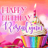 A vibrant birthday GIF featuring a rainbow-colored cupcake topped with white frosting, sprinkles, and a lit candle. The text reads 'Happy Birthday Rosealynn' in bold pink and violet letters with white outline.