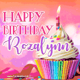 A vibrant birthday GIF featuring a rainbow-colored cupcake topped with white frosting, sprinkles, and a lit candle. The text reads 'Happy Birthday Rozalynn' in bold pink and violet letters with white outline.