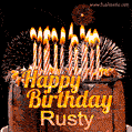 A rich chocolate cake topped with glowing birthday candles and surrounded by bright fireworks. The animated GIF displays the message 'Happy Birthday Rusty' in golden text.