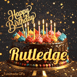 A chocolate frosted birthday cake on a gold stand with lit candles and the name Rutledge in bold yellow letters.