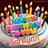 A colorful birthday cake topped with lit candles, with the words 'Happy Birthday Sarayah' in bold glowing letters on a burgundy background. Animated flames add a festive touch.