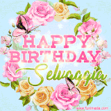 A charming animated GIF featuring 'Happy Birthday Selvaggia' in pink and green text, surrounded by delicate roses, leaves, and fluttering butterflies on a soft light blue pastel background.