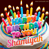 A colorful birthday cake topped with lit candles, with the words 'Happy Birthday Shamiyah' in bold glowing letters on a burgundy background. Animated flames add a festive touch.