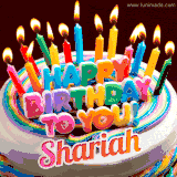 A colorful birthday cake topped with lit candles, with the words 'Happy Birthday Shariah' in bold glowing letters on a burgundy background. Animated flames add a festive touch.