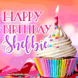 A vibrant birthday GIF featuring a rainbow-colored cupcake topped with white frosting, sprinkles, and a lit candle. The text reads 'Happy Birthday Shelbie' in bold pink and violet letters with white outline.