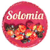 Beautifully decorated red velvet berry birthday cake with vibrant fruits and a glowing 'Solomia' name, adding a touch of sweetness and sparkle.