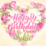 A stunning heart made of pink roses surrounds the elegant script text 'Happy Birthday Sukie' on a soft beige background. Animated sparkles add a magical and festive feel.