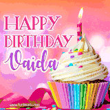 A vibrant birthday GIF featuring a rainbow-colored cupcake topped with white frosting, sprinkles, and a lit candle. The text reads 'Happy Birthday Vaida' in bold pink and violet letters with white outline.
