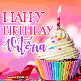 A vibrant birthday GIF featuring a rainbow-colored cupcake topped with white frosting, sprinkles, and a lit candle. The text reads 'Happy Birthday Vitória' in bold pink and violet letters with white outline.