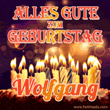 An animated GIF featuring 'Alles Gute Zum Geburtstag Wolfgang' in glowing red and gold letters above a cake with colorful lit candles, set against a festive sparkling background.