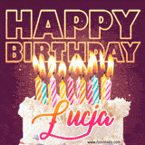 A colorful birthday cake topped with lit candles, with the words 'Happy Birthday Łucja' in bold glowing letters on a burgundy background. Animated flames add a festive touch.