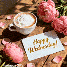 Top-down view of a frothy cappuccino cup on a rustic wooden table surrounded by pink lush peonies and loose petals, next to a white card featuring gold 'Happy Wednesday!' calligraphy.